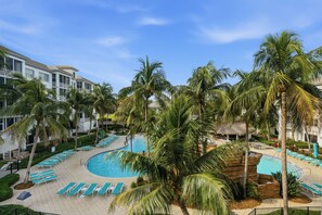 A resort with a pool surrounded by palm trees and lounge chairs. - PICKED TOP BONITA CONDO, 85" SMART TV. RESORT POOL VIEW (Bonita Springs)