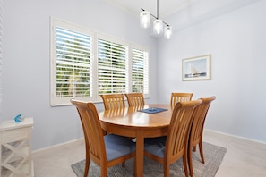 A dining area with a round wooden table, six chairs, and a view through open windows with palm trees. - PICKED TOP BONITA CONDO, 85" SMART TV. RESORT POOL VIEW (Bonita Springs)