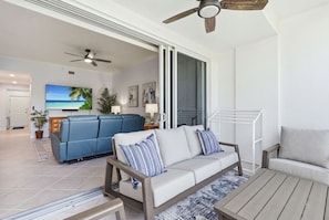 A modern living room with a sofa, a coffee table, and a ceiling fan. - PICKED TOP BONITA CONDO, 85" SMART TV. RESORT POOL VIEW (Bonita Springs)