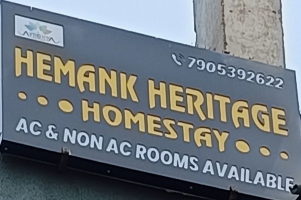 Letrero de Hemank Heritage Homestay que anuncia habitaciones con y sin aire acondicionado.