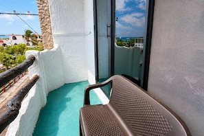 Un balcón con vista al mar, una silla y una pared blanca.