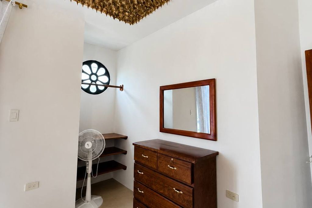 Une pièce avec une commode en bois, un miroir et un ventilateur.