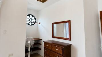 Une pièce avec une commode en bois, un miroir et un ventilateur.
