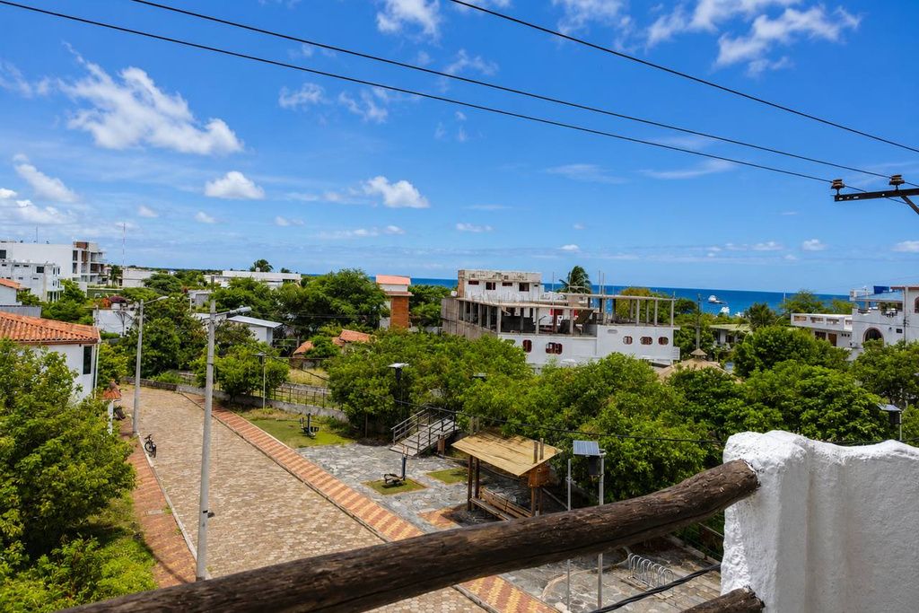 Un pueblo costero con edificios, una calle pavimentada y vista al mar.