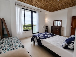 Un dormitorio con dos camas, una ventana con cortinas, un ventilador, un aparador y una escalera de madera.