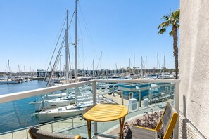 Een balkon met uitzicht op een jachthaven, met boten en een heldere lucht.