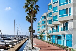 A marina with boats docked, a row of palm trees, and modern buildings with balconies. - Coral Marina' Water Views Pool Jacuzzi Sauna Gym (Marina del Rey)