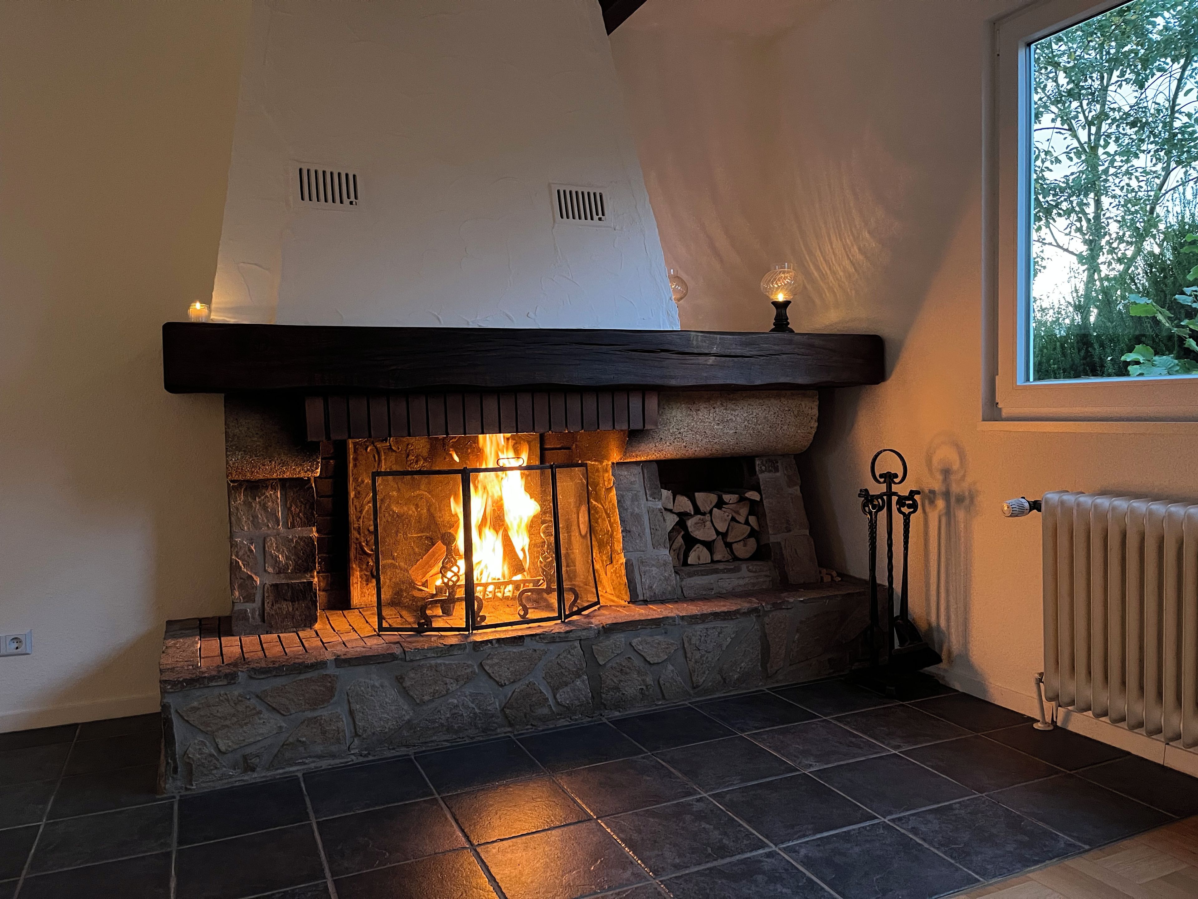 Une cheminée avec un foyer en pierre, une étagère et un espace de rangement pour le bois.