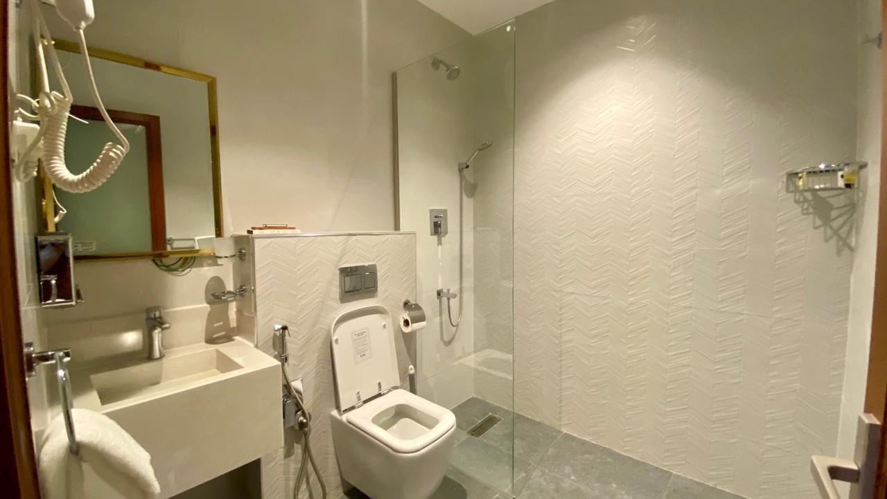 Un baño moderno con ducha envuelta en vidrio, inodoro y lavamanos.