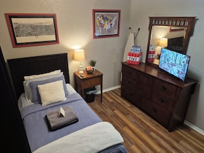 A bedroom with a bed, a nightstand, a dresser, a television, and wall decorations. - Serene 1-bedroom house with AC in Tulsa perfect for relaxing (Tulsa)
