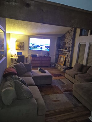 A living room with a stone fireplace, a television, and a sofa. - Serene 1-bedroom house with AC in Tulsa perfect for relaxing (Tulsa)