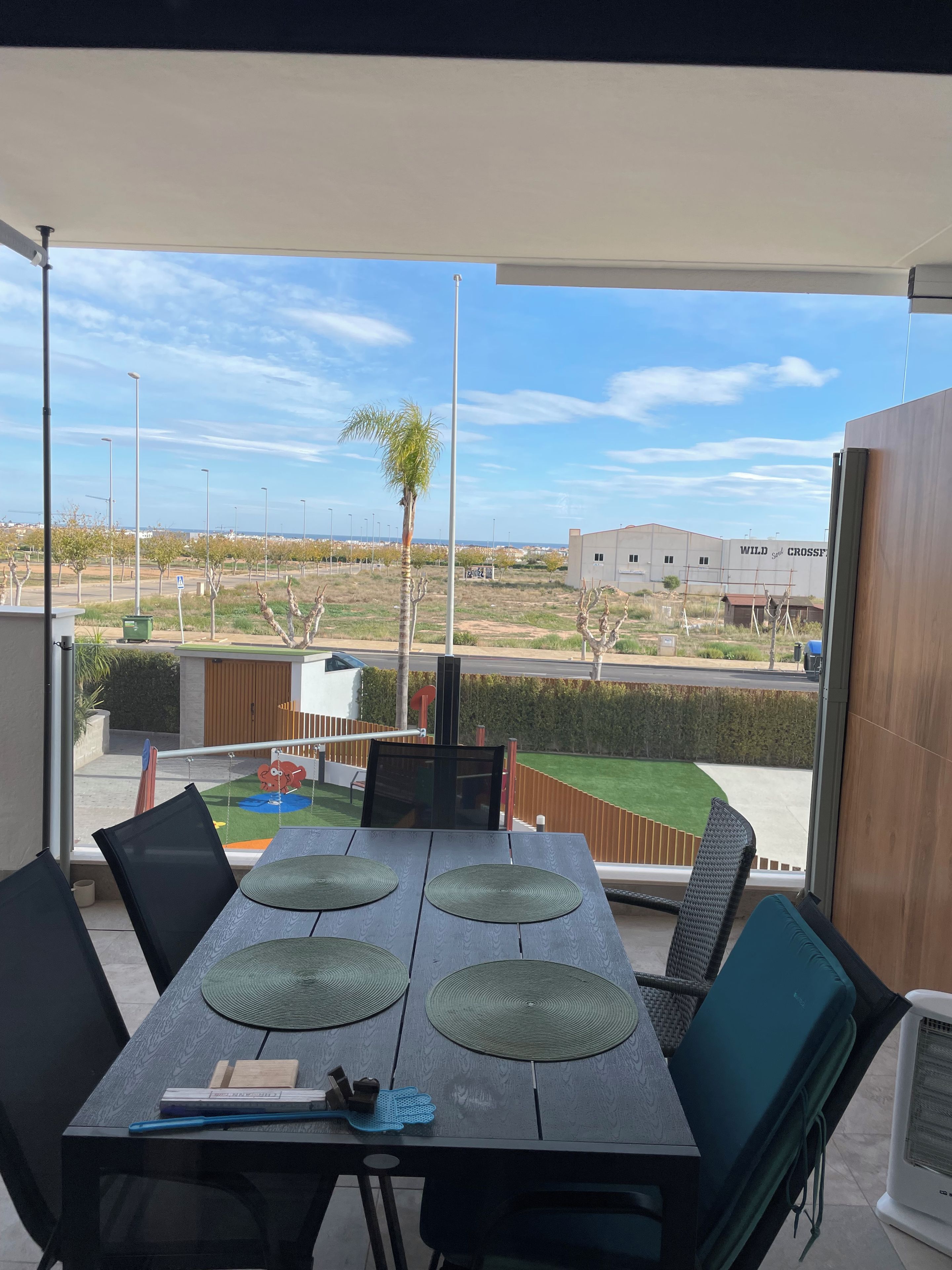 A balcony with a table, chairs, and a view of a residential area.