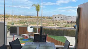 A balcony with a table, chairs, and a view of a residential area.