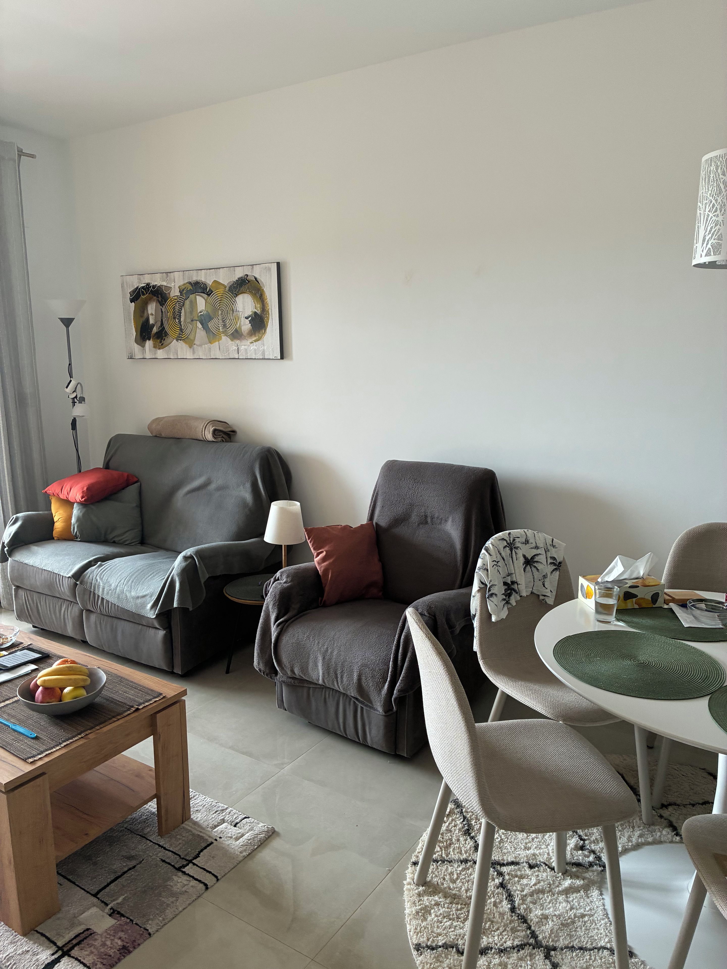 A modern living room with a sofa, armchairs, a coffee table, and a dining table.