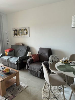 Una sala de estar moderna con un sofá, sillones, una mesa de centro y una mesa de comedor.