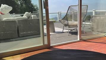 A room with a view of outdoor seating, a table with teapots and cups, and a large glass door.