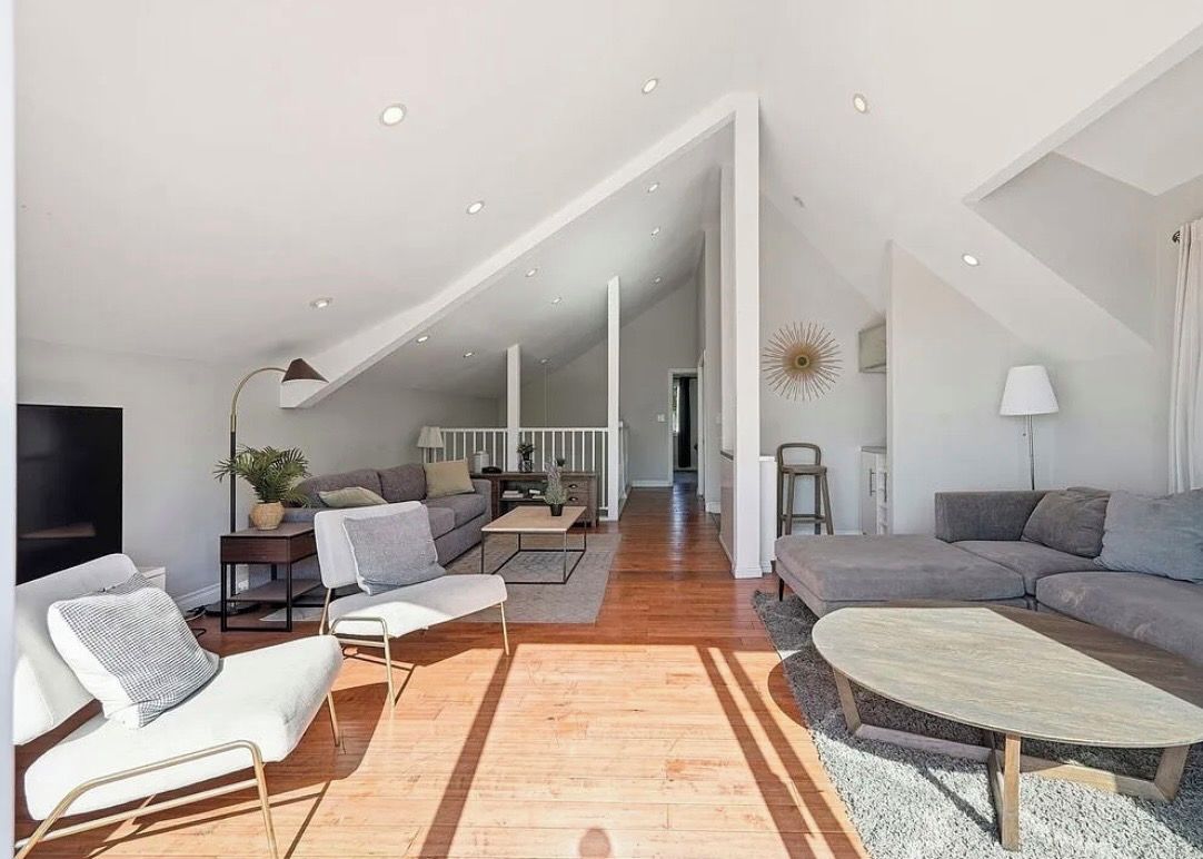 A spacious living area with a high ceiling, a sofa set, a coffee table, and a television.