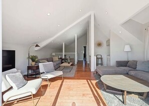 A spacious living area with a high ceiling, a sofa set, a coffee table, and a television. - Malibu Hills Picturesque  Oceanview Three Bedrooms Close to Beach and Pepperdine (Malibu)