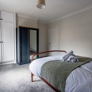 A bedroom with a bed, a wardrobe, and a door. - Central Bishop Auckland - House - Sleeps 4 (Bishop Auckland)