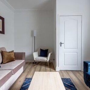 A room with a sofa, a chair, a door, and a lamp. - Central Bishop Auckland - House - Sleeps 4 (Bishop Auckland)