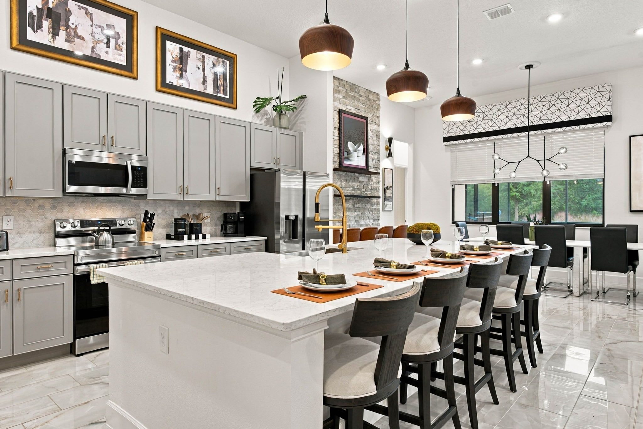 A modern kitchen with a large island, stainless steel appliances, and pendant lighting.
