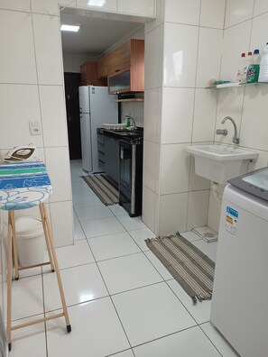 Een functionele keuken met een koelkast, fornuis, spoelbak en houten kastjes.