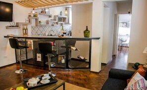 A modern kitchen with a bar area, a dining table, and a living room with a sofa. - Comfortable and cozy apartment in a great location (Mendoza)