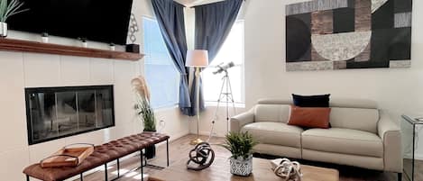 A modern living room with a flat-screen TV, a sofa, a coffee table, and a bench.