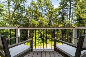 A wooden deck with two benches and a railing, overlooking a forested area. - 6BR Poconos Home - Indoor Heated Pool & Hot Tub - Theater, Gym and Game Room (Cresco)