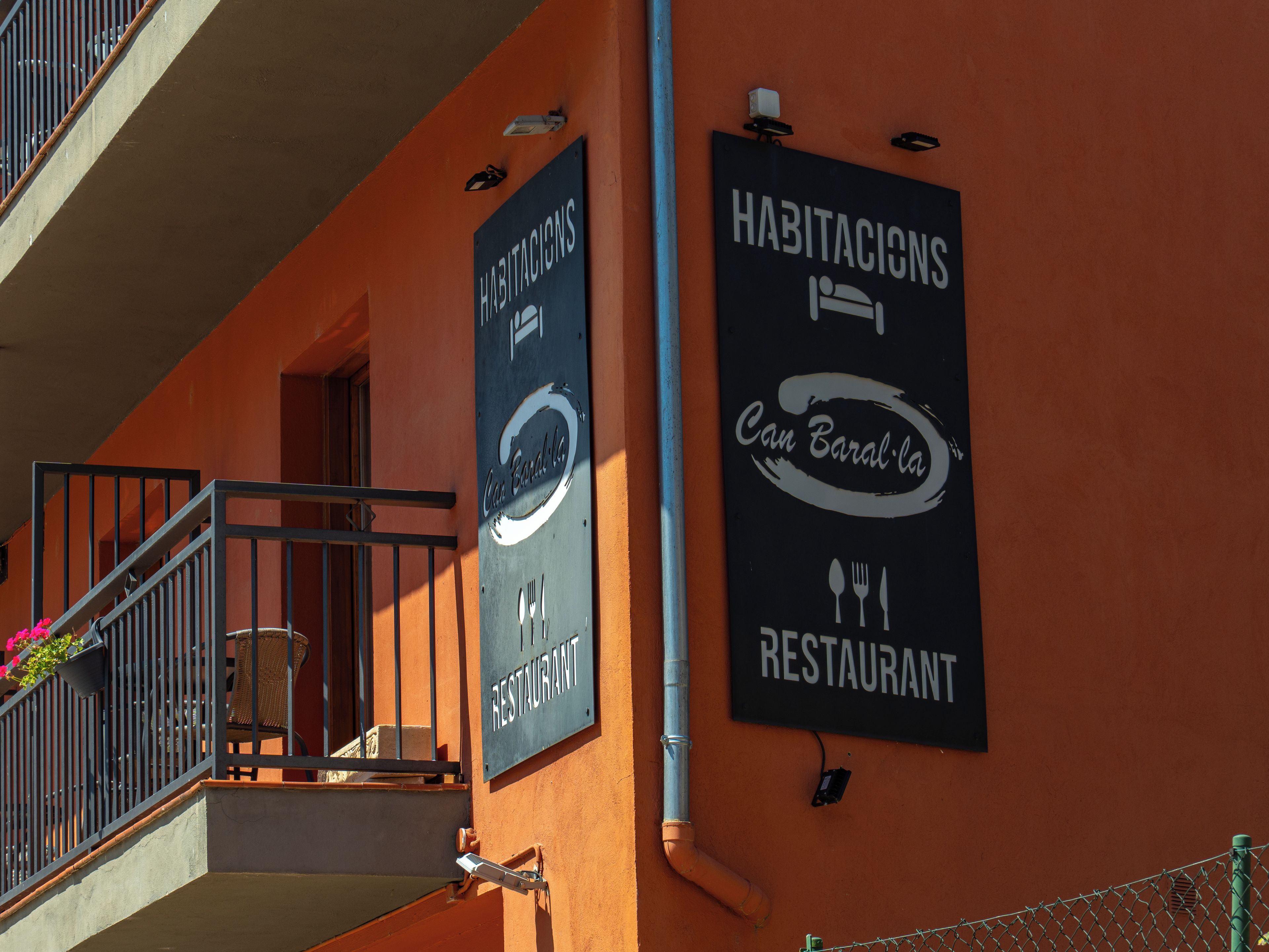 Un edificio con un letrero que indica un restaurante y un letrero que dice 'Habitacions Can Baral la'.