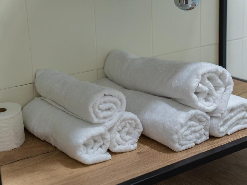 A stack of white towels on a wooden shelf in a bathroom.