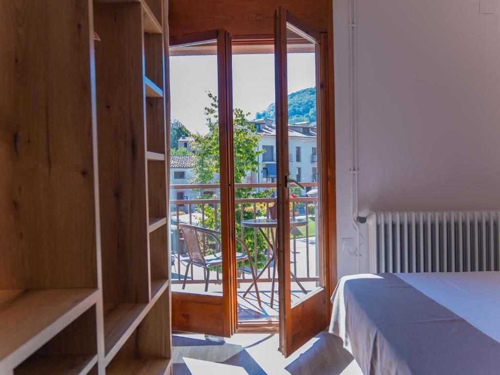Una habitación con una cama, un radiador y vistas a un balcón con sillas y una mesa.