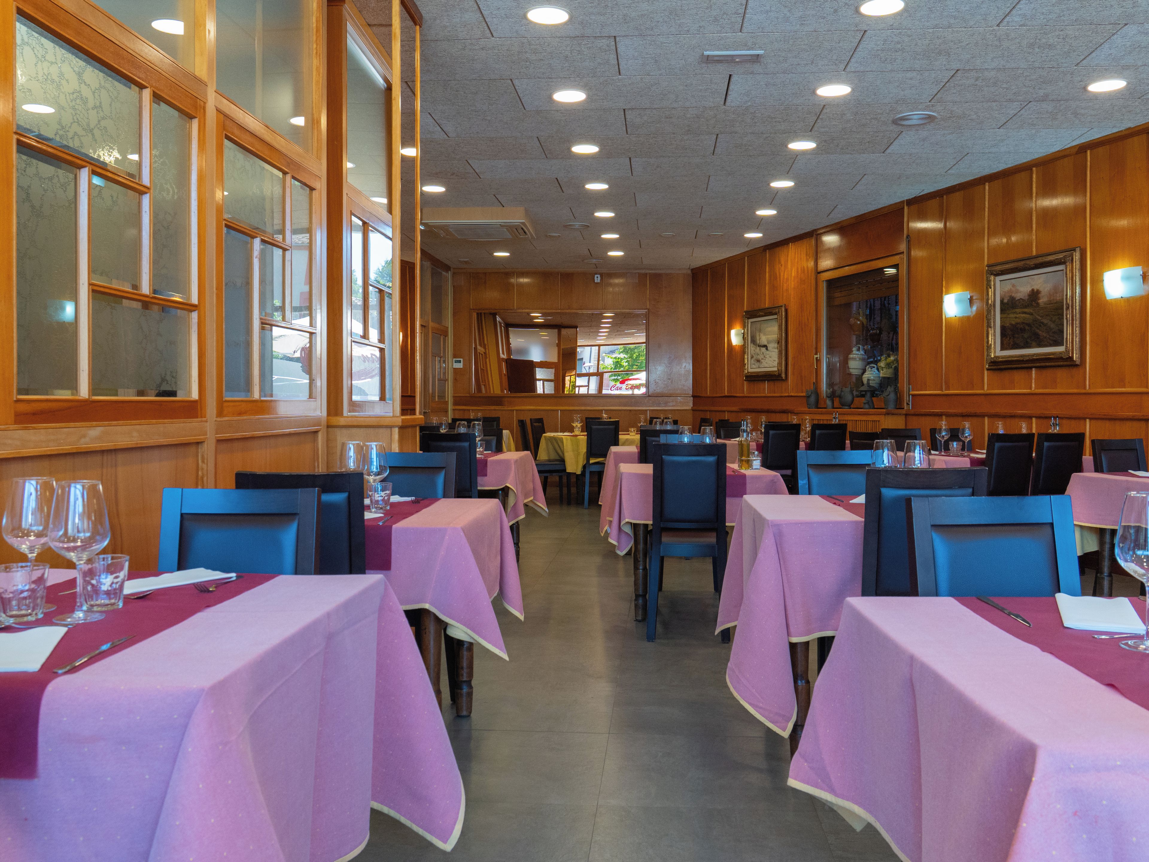 A restaurant interior with multiple tables, chairs, and a view of the street through large windows.