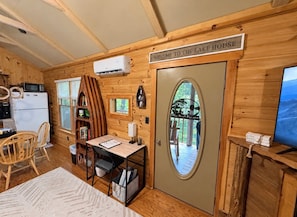 A wooden cabin interior with a dining area, kitchen, and a door leading to a deck. - The Reel Escape (Dahlonega)