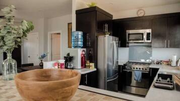 Een moderne keuken met donkere kastjes, roestvrijstalen apparatuur en een grote houten kom op het aanrecht.