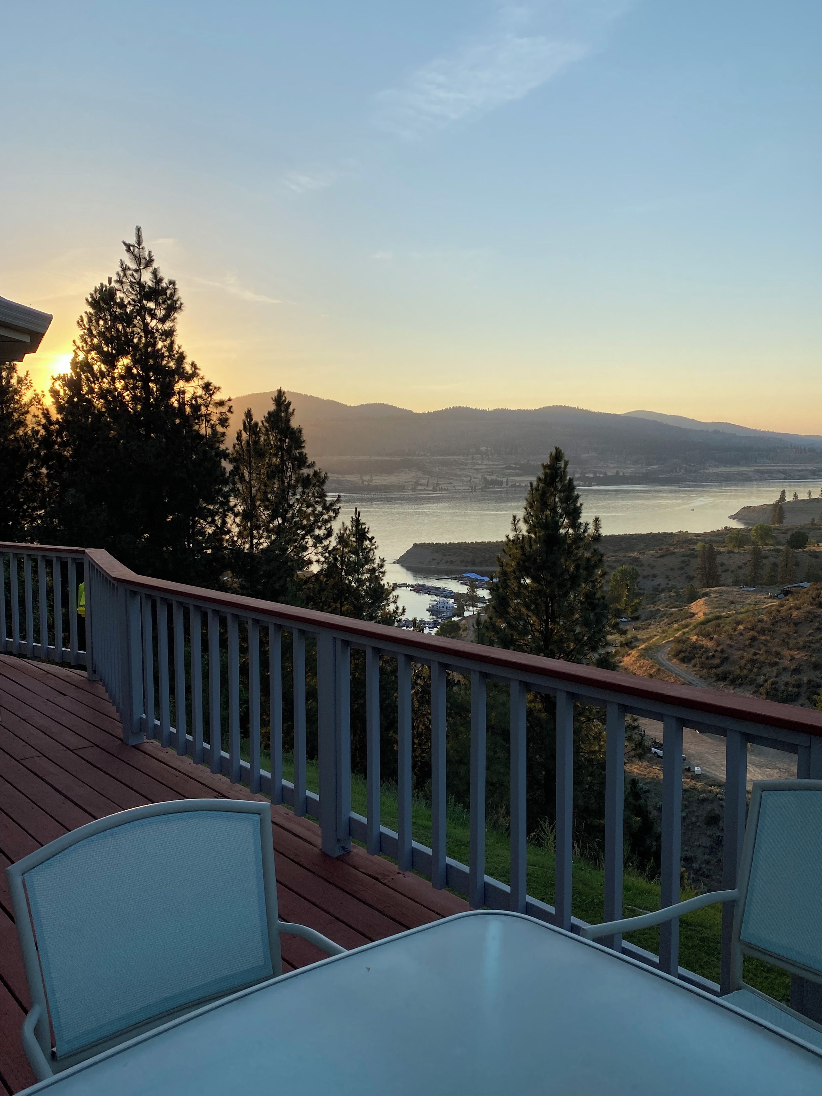 Une terrasse offrant une vue sur une rivière et des collines lointaines.