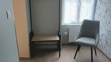 Una habitación con una cama, una silla y una ventana.