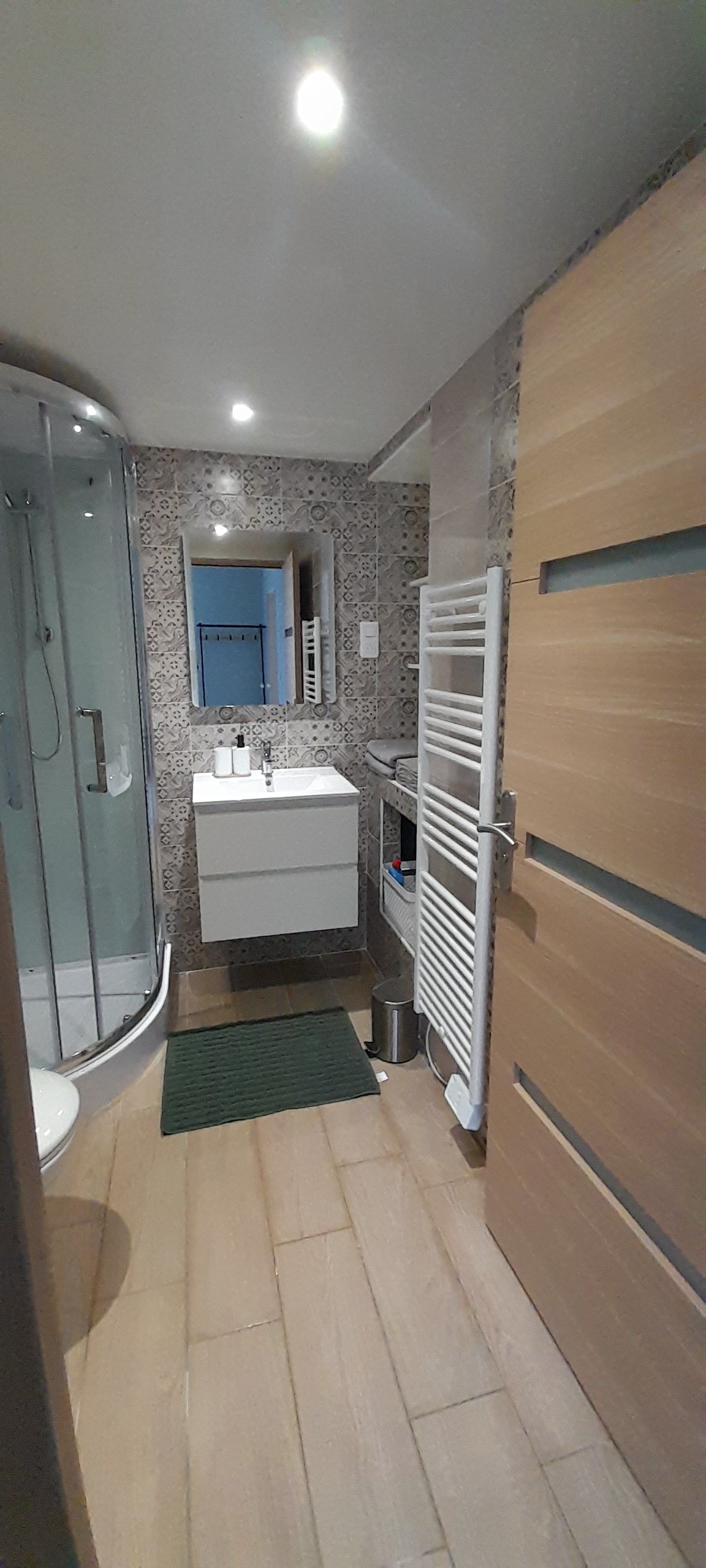 A compact bathroom with a glass shower enclosure, a white sink, and a towel rack.
