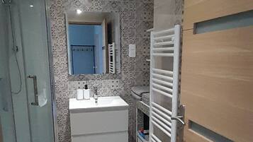 A compact bathroom with a glass shower enclosure, a white sink, and a towel rack.
