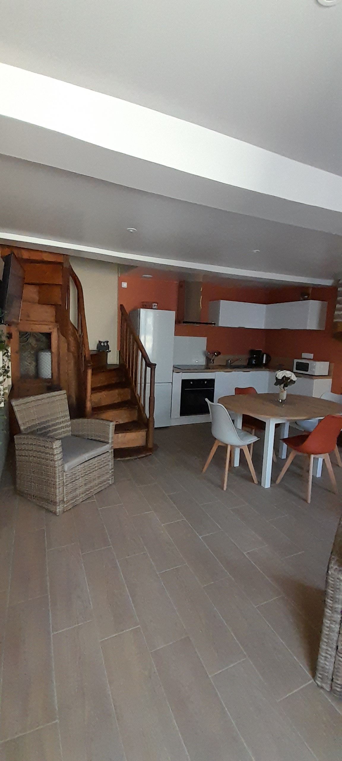 A modern kitchen with a dining area, a staircase, and a seating arrangement.
