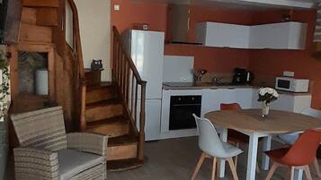 A modern kitchen with a dining area, a staircase, and a seating arrangement.