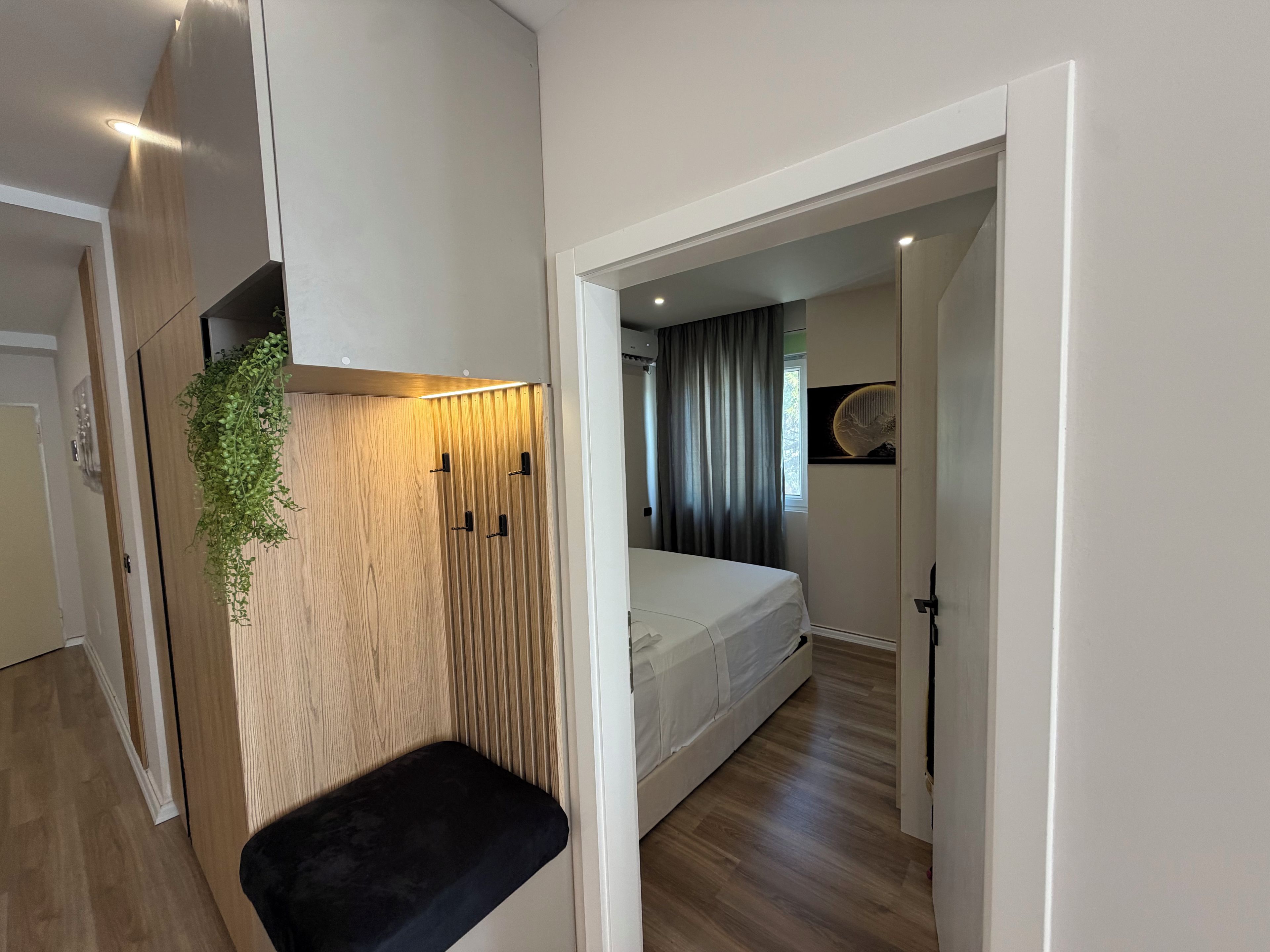 A modern bedroom with a bed, a bench, and a wall-mounted plant.
