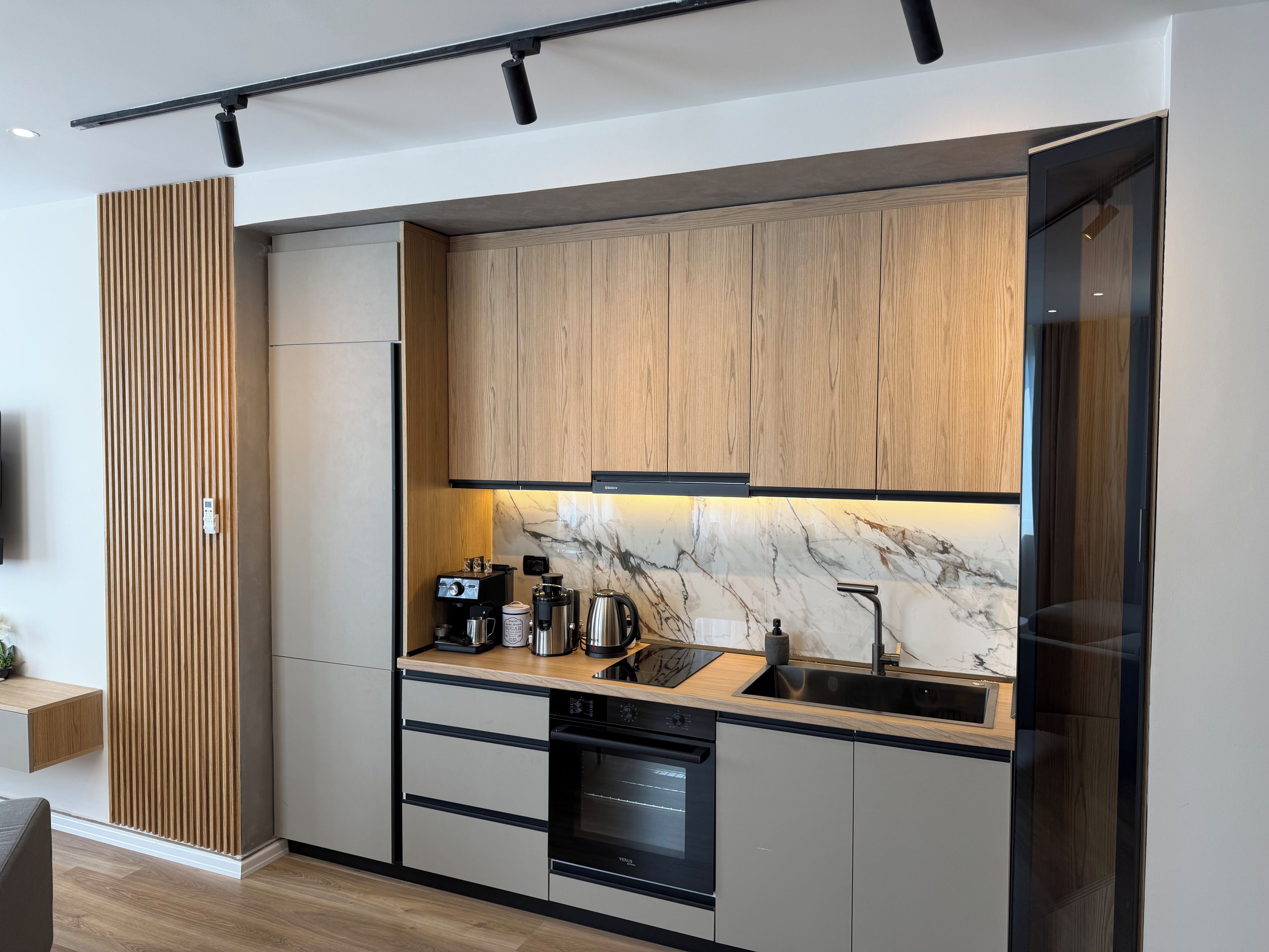 Eine moderne Küche mit Holzausstattung, einer Marmor-Spritzschutzwand und integrierten Geräten.