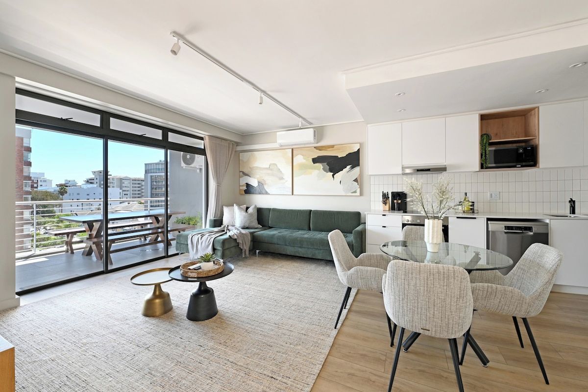 Un appartement moderne doté d’un balcon, d’un coin repas et d’une cuisine.