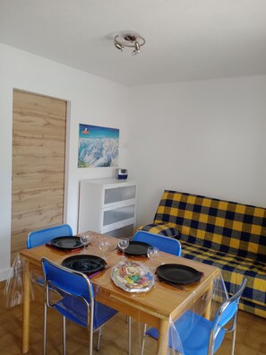 A dining area with a wooden table, blue chairs, and a checkered sofa. - Mountain studio apartment with sleeping alcove for 4 people in Saint-Lary-Soulan, renovated in 2026. (Saint-Lary-Soulan)