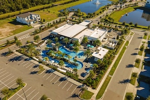 A hotel with a swimming pool, parking lot, and a large building with a flat roof. - Luxury 15br Suites Pool and Themed Bedrooms (Orlando)