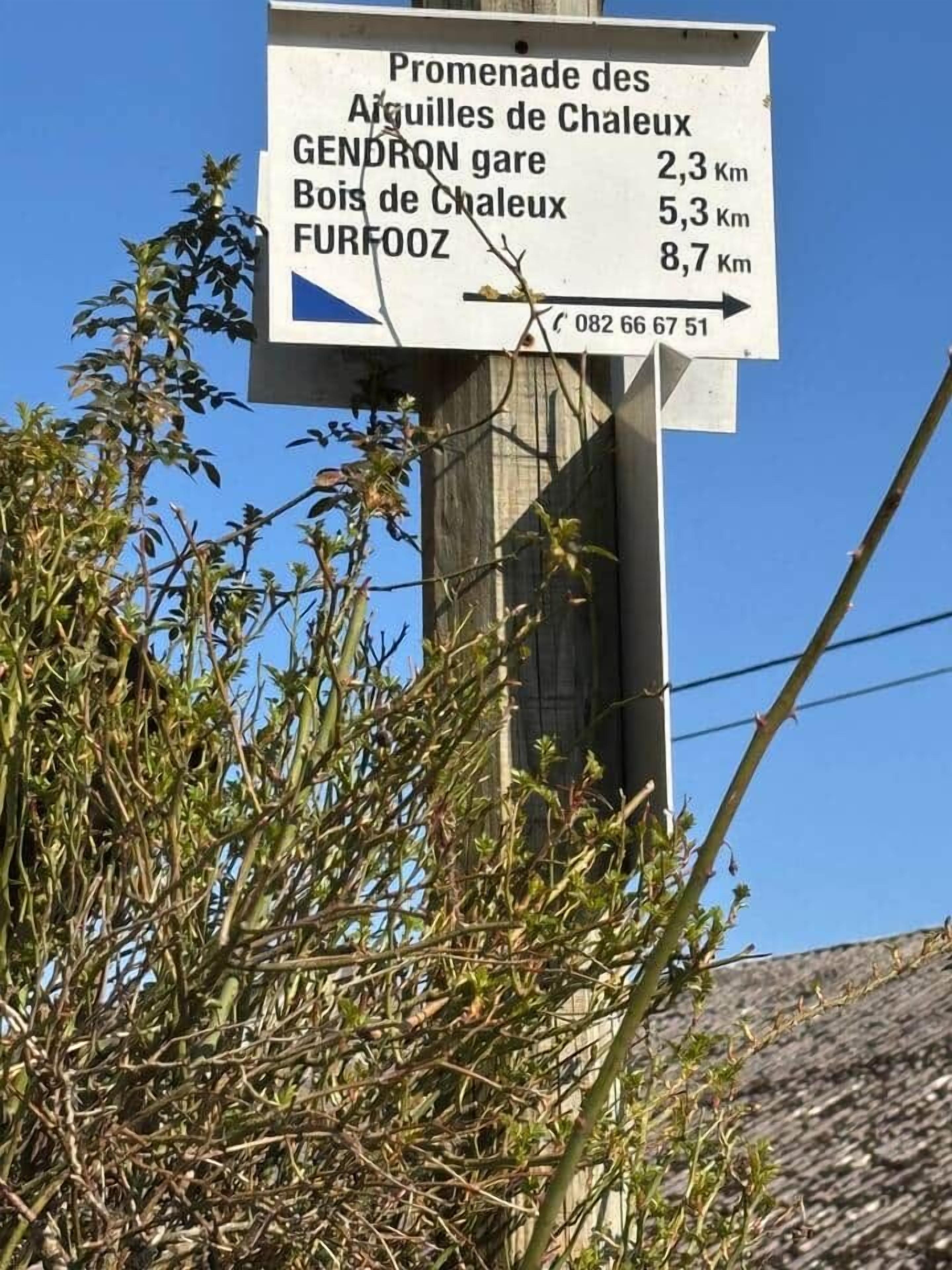 A directional signpost with distance markers to Gendron gare, Bois de Chaleux, and Furfoo.