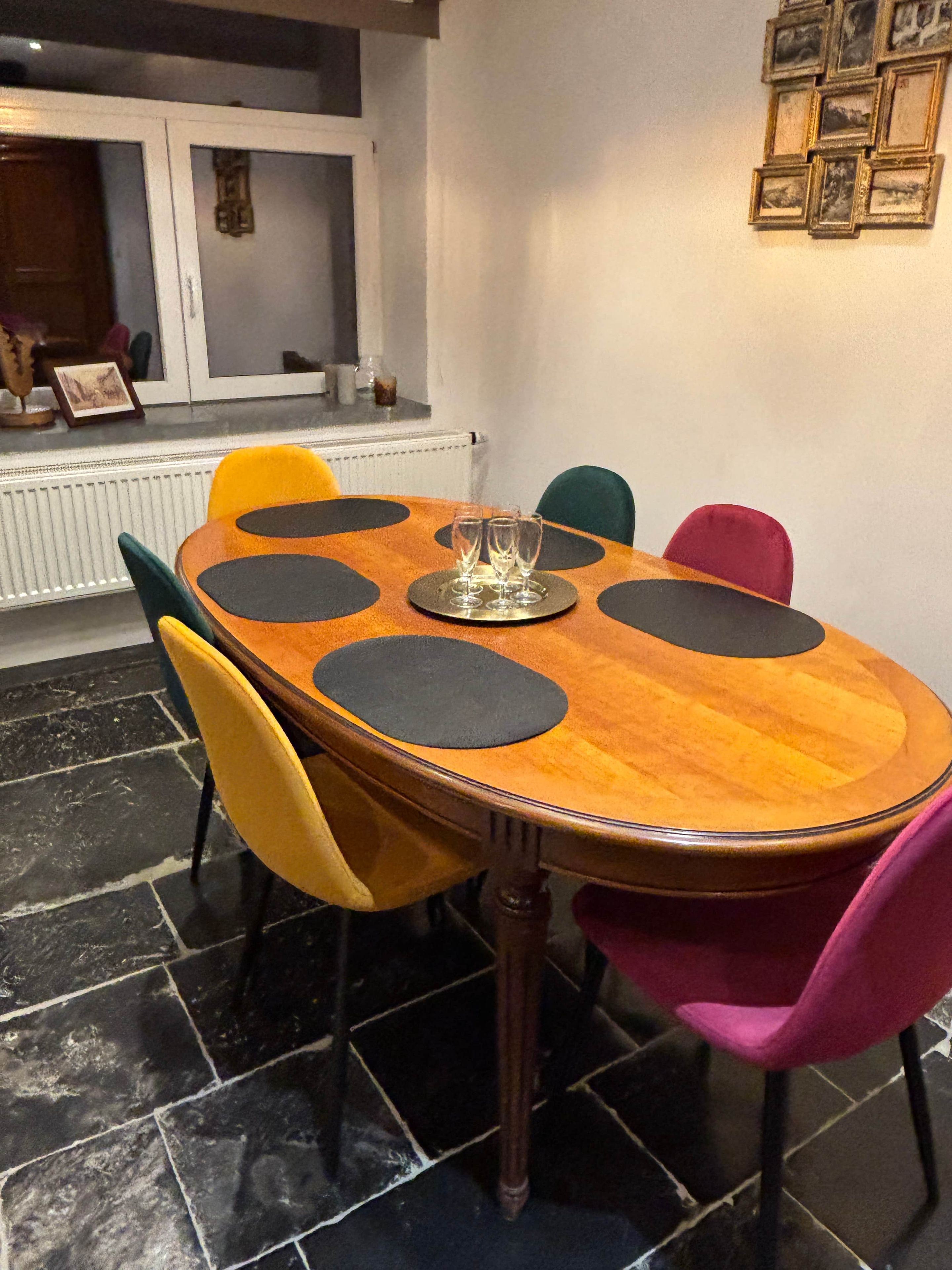 Een eettafel met een rond houten blad, omringd door stoelen met zwart en gele kussens.