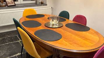 Een eettafel met een rond houten blad, omringd door stoelen met zwart en gele kussens.