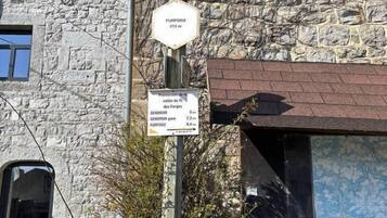 A stone building with a sign indicating 'Furfooz 212 m' and 'Promenade de la vallée du R. Gendron 5.4'.